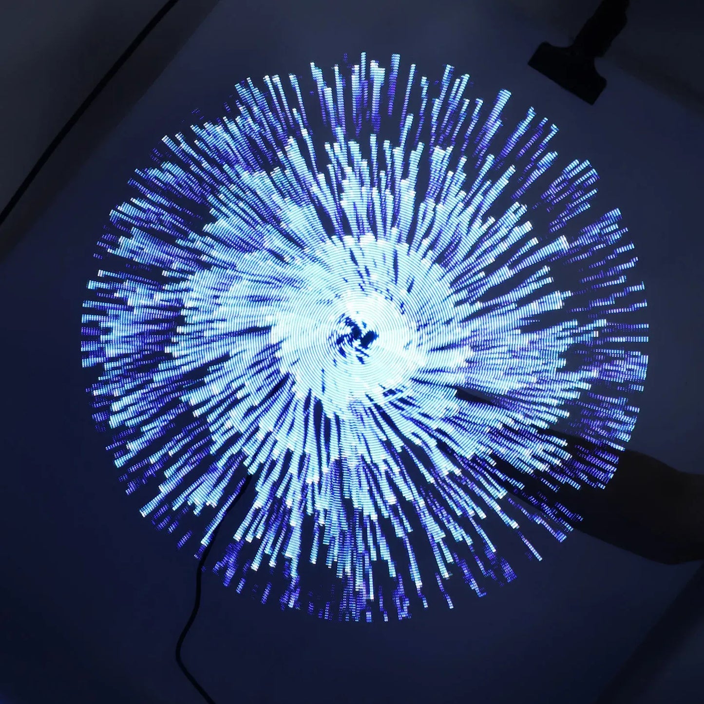 Circular light display with blue and white lights on a dark background