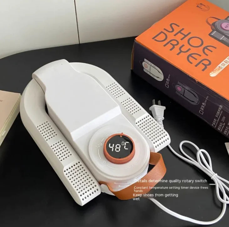 White shoe dryer with digital display on a black surface, next to its packaging box.