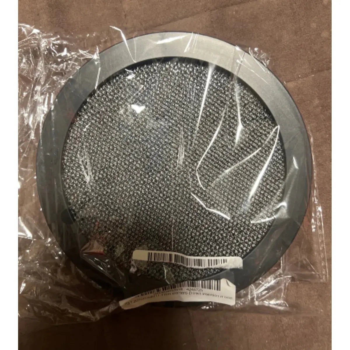 Round metallic filter in clear plastic packaging on a brown background